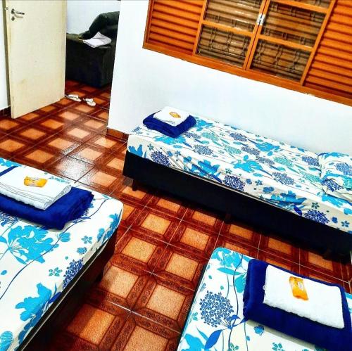 two beds in a room with blue and white sheets at Hospedagem Rosa Branca in Uberlândia
