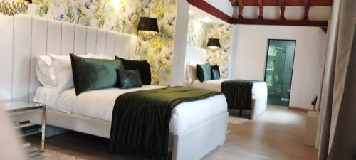 a bedroom with a white bed with a green blanket at Hotel Boutique Guatika in Tibasosa