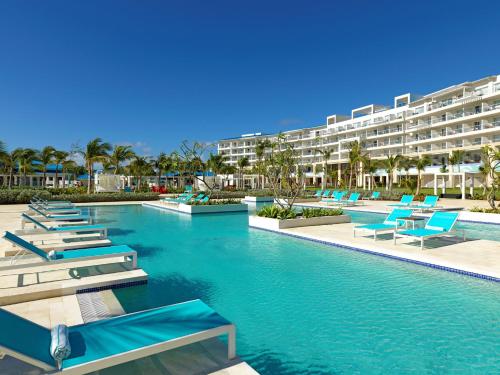 a resort swimming pool with blue chairs and a building at Margaritaville Island Reserve Cap Cana Wave - An All-Inclusive Experience for All in Punta Cana