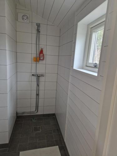 y baño de azulejos blancos con ducha y ventana. en Fräscht, spatiöst hus, en Visby