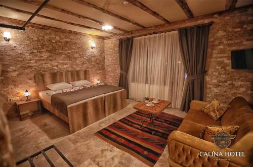 a bedroom with a bed and a couch and a chair at Calina Hotel in Uçhisar