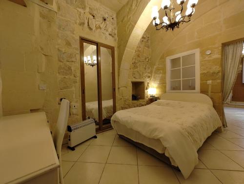 a bedroom with a large bed and a mirror at Charming rustic getaway in Xaghra, Gozo. in Xagħra