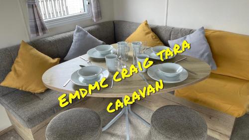 a table with plates and glasses on a couch at EMDMC Craig Tara Caravan in Ayr