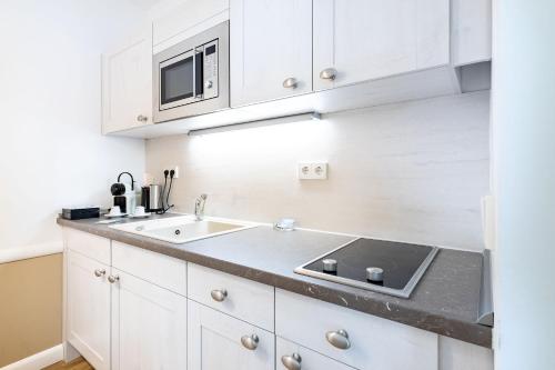 a white kitchen with a sink and a microwave at Victoria Suites in Bad Saarow