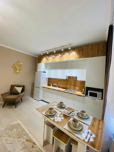 ein Wohnzimmer mit einem Tisch und einer Küche in der Unterkunft Уютные апартаменты центр города в новом ЖК Арман in Atyrau