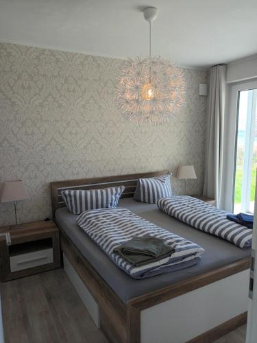 a bedroom with a large bed with a chandelier at Ferienwohnung MeerZeit EG in Altefähr