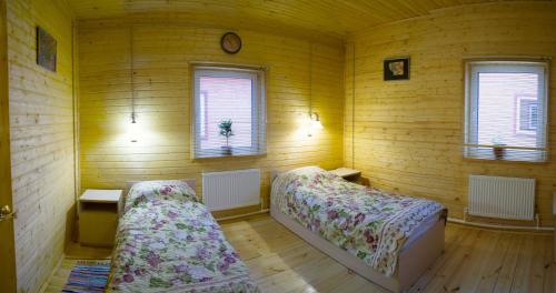 two beds in a room with wooden walls and windows at Ramanov Plyos Guest House in Vladimir