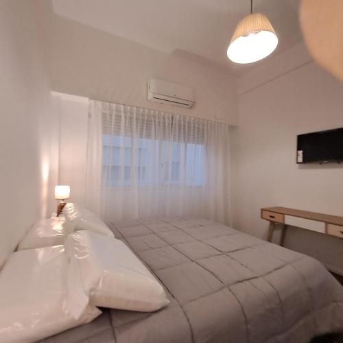 a white bedroom with a large bed with a window at Down Town Telmo in Buenos Aires