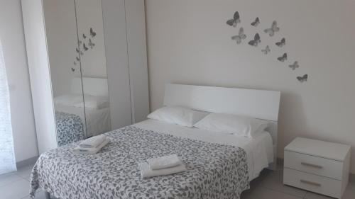 a white bedroom with a bed with two towels on it at RANDAZZO SUITES - Liv 3 - Appartamento Vacanze - Prima chiamaci in Randazzo