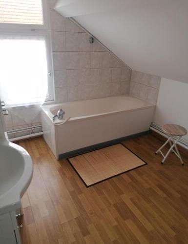 La salle de bains est pourvue d'une baignoire blanche et d'une fenêtre. dans l'établissement Aux Oyats d Isa, à Fort-Mahon-Plage