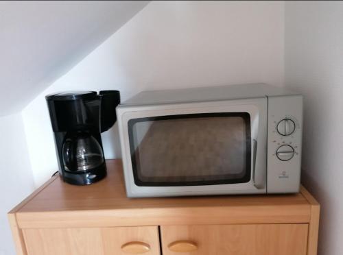 Un four micro-ondes est installé au-dessus d'une armoire en bois. dans l'établissement Aux Oyats d Isa, à Fort-Mahon-Plage