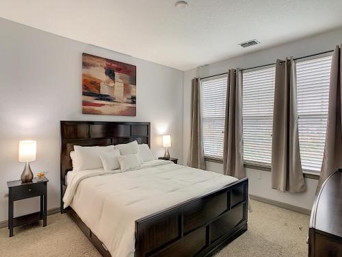 a bedroom with a large bed and two windows at Convenient And Close To All in Kissimmee