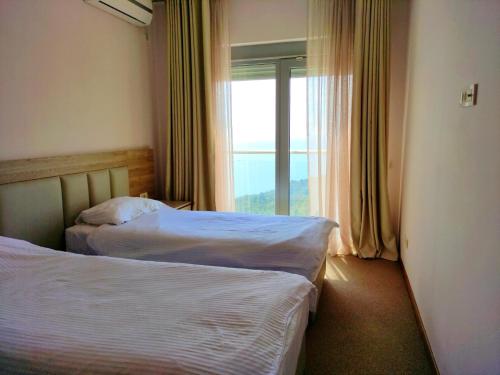 twee bedden in een hotelkamer met een raam bij Skyline View Apt & Pool Retreat in Budva