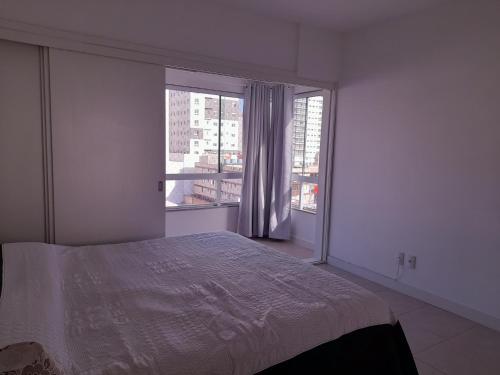 um quarto com uma cama e uma grande janela em Confortável apartamento na praia em Capão da Canoa
