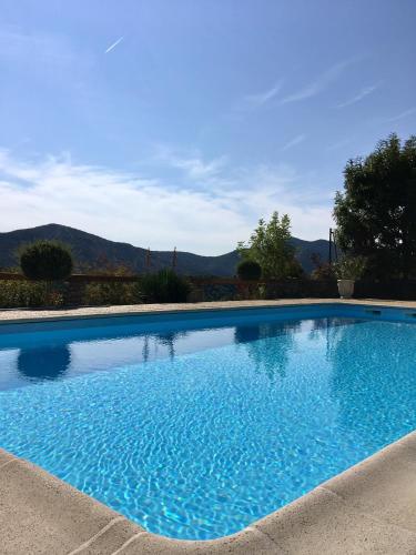 une grande piscine bleue avec des montagnes en arrière-plan dans l'établissement La Grange Vercors, à Les Maillets