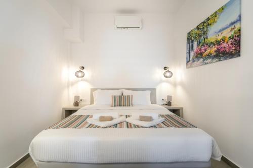 a bedroom with a white bed with two towels on it at SN Santorini Apartments in Kamari