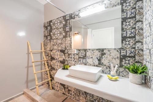 La salle de bains est pourvue d'un lavabo blanc et d'un miroir. dans l'établissement SN Santorini Apartments, à Kamari