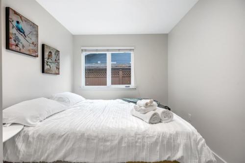 een witte slaapkamer met een bed met handdoeken erop bij Luxury Delta 2BD Suit on ground floor in Delta