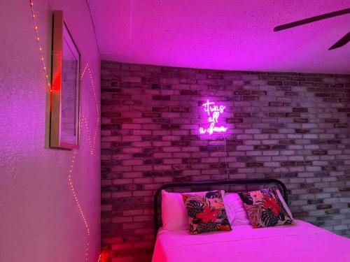 a room with a bed with a neon sign on a brick wall at Apartment near TPA Airport in Tampa