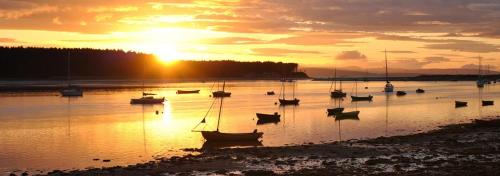 a group of boats in the water at sunset at Driftwood Cottage, Findhorn Village in Forres