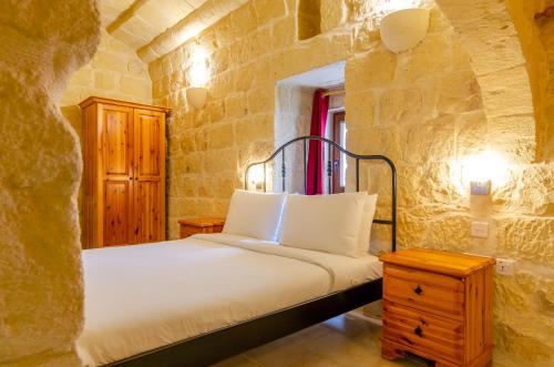 a bedroom with a bed in a stone wall at Country Stays Hostel in Sannat