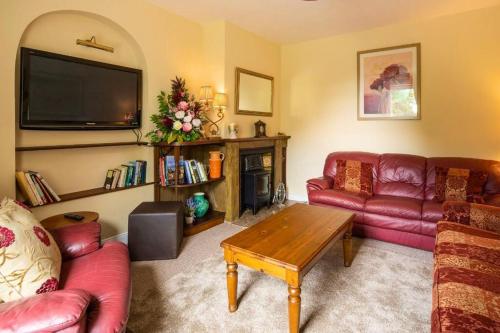 a living room with red couches and a tv at Lime Tree House in Maguires Bridge