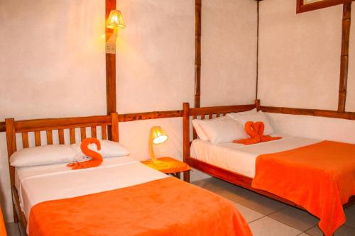 2 camas en una habitación con sábanas de color naranja en HANGA ROA HOTEL, en Montañita