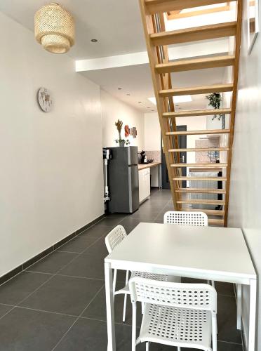 une salle à manger avec une table et des chaises blanches dans l'établissement Gîte Shaka, à Gravelines