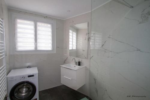 La salle de bains blanche est pourvue d'un lave-linge et d'un lavabo. dans l'établissement L'Inattendu - Les Maisons de Madeleine, à Nantes