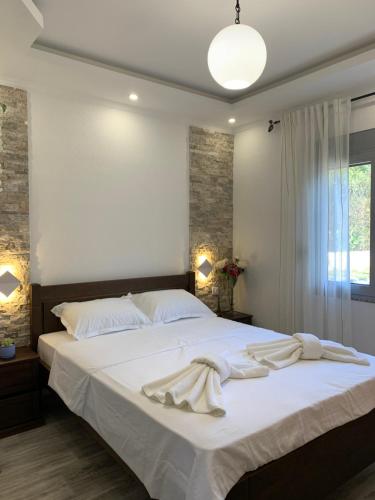 1 dormitorio con 1 cama grande con sábanas blancas en Markovic Village Apartments, en Ulcinj