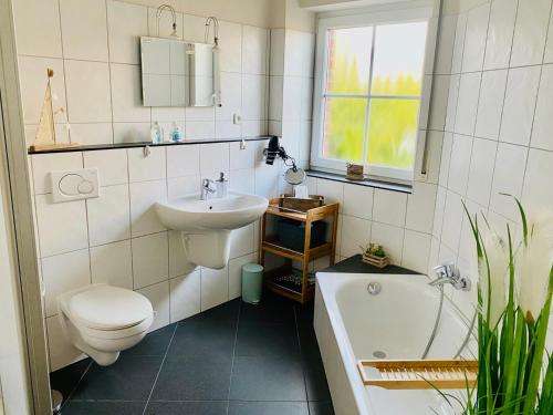 une salle de bain avec toilettes, lavabo et baignoire dans l'établissement FeWo SONNENDECK Familien-strandnah-Garten-Hunde-Sport-und Schwimmbadnah-HansaPark, à Sierksdorf