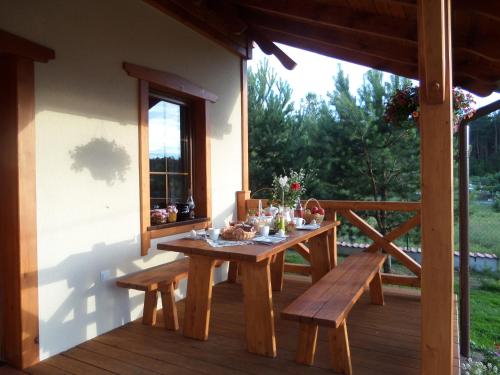 une table en bois et des bancs sur la terrasse couverte d'une maison dans l'établissement Domek 12 osobowy na Kaszubach - Agrowczasy U PIANKA, 