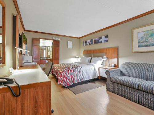 Habitación de hotel con cama y sofá en Red Roof Inn Uhrichsville, en Uhrichsville