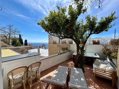 eine Terrasse mit einem Tisch, Stühlen und einem Baum in der Unterkunft Villa Fortuna in Positano