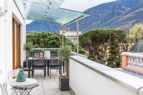 a balcony with a table and chairs and mountains at Luxus Penthouse mit Terrasse, Garage, Fahrradraum und Infrarotsauna in Merano