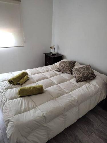a white bed with two pillows on it in a room at Espacioso y cómodo departamento in La Cieneguita