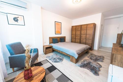 a bedroom with a bed and a chair and a table at EVRA APARTMENTS in Recaş