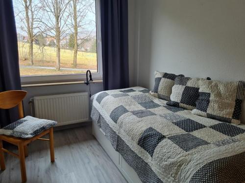 a bedroom with a bed and a window and a chair at Große Wohnung - Kamin - Balkon - Boxspringbett - Skiwiese in Braunlage