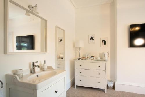 a white bathroom with a sink and a mirror at 3 Bedroom villa attached to Host home free parking in Perth