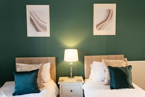 two beds in a room with green walls at 3 Bedroom villa attached to Host home free parking in Perth