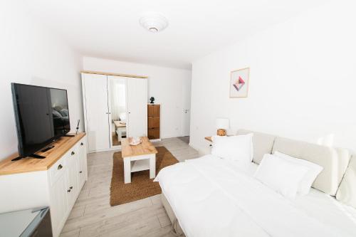 a white living room with a white couch and a television at EVRA APARTMENTS in Recaş