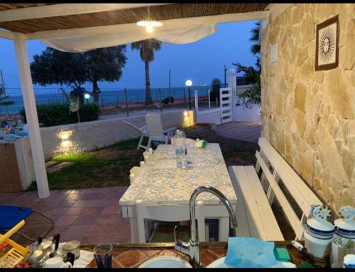 un patio con una mesa y una cocina con el océano en san lorenzo a 4 mt dal mare colore smeraldo a due passi da Marzamemi, en Reitani