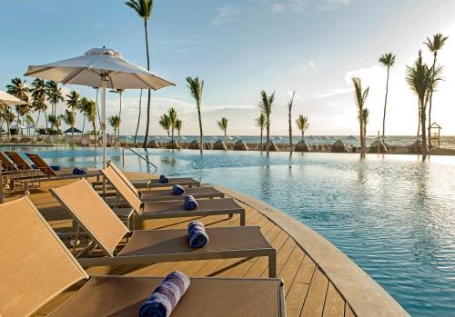 uma piscina num resort com cadeiras e palmeiras em Nickelodeon Hotels & Resorts Punta Cana - Gourmet All Inclusive by Karisma em Punta Cana