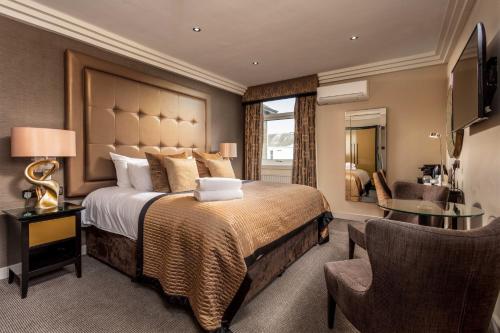 a hotel room with a large bed and a chair at The Kylestrome in Ayr