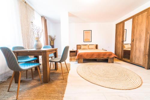 ein Wohnzimmer mit einem Tisch, Stühlen und einem Bett in der Unterkunft EVRA APARTMENTS in Recaş