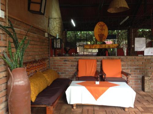 a patio with a bed and two orange chairs at Outpost Lodge in Arusha