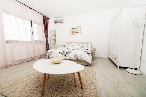 a white bedroom with a bed and a table at EVRA APARTMENTS in Recaş