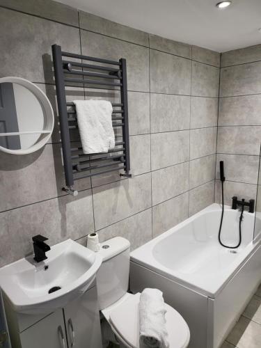 a bathroom with a sink and a toilet and a tub at Vetrelax Southend Apartment in Westcliff-On-Sea