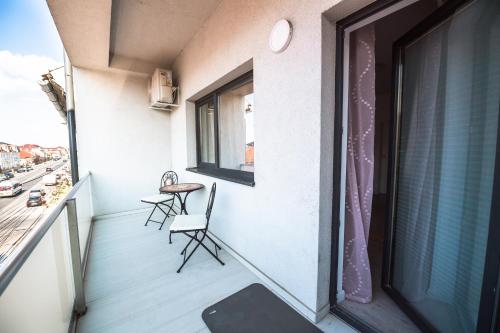 a balcony with a table and chairs and a window at EVRA APARTMENTS in Recaş