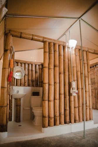 a bathroom with a toilet and a bamboo wall at Serrano Tayrona Lodge in El Zaino